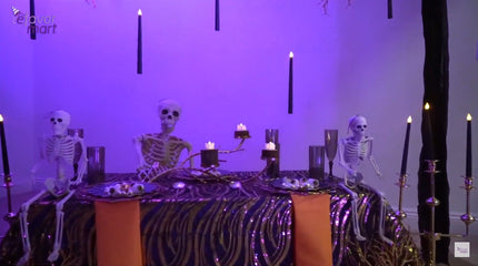 Setting up a gold backdrop stand with floating LED taper candles for a Halloween table decor.