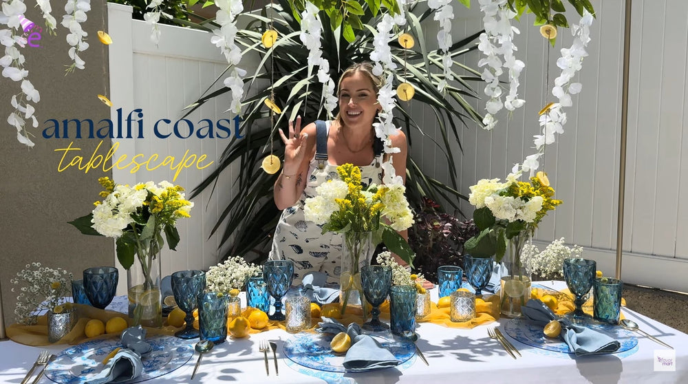 Amalfi Coast summer tablescape with flowers, blue glassware, and lemons.