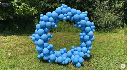 Fully assembled circular blue balloon arch displayed outdoors on the grass.