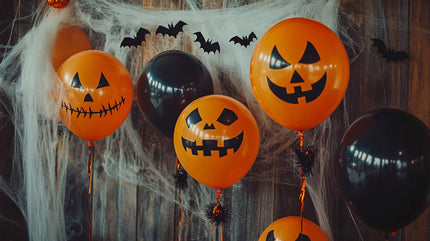 Close-up of Halloween decor with black and orange balloons and cobwebbed backdrop featuring bats.