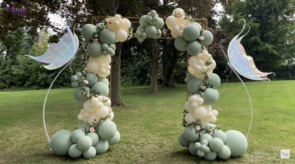 Completed fairy-inspired balloon arch with dusty sage green, beige balloons, and floral accents.