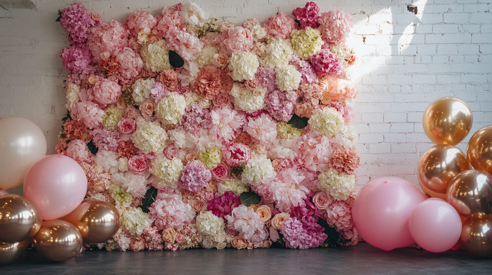 Pastel balloons and lush florals arranged in a soft pink flower wall backdrop