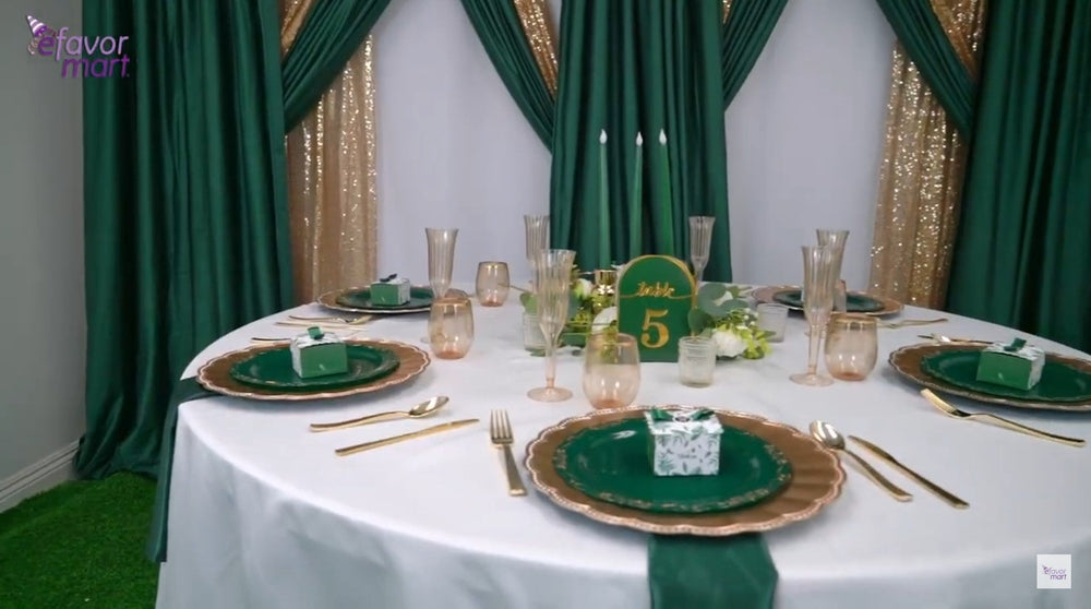 Elegant emerald and gold event table setup with centerpiece and glassware.