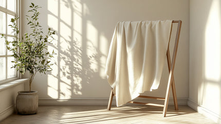 A light-colored linen draped over a wooden drying rack in a sunlit room.